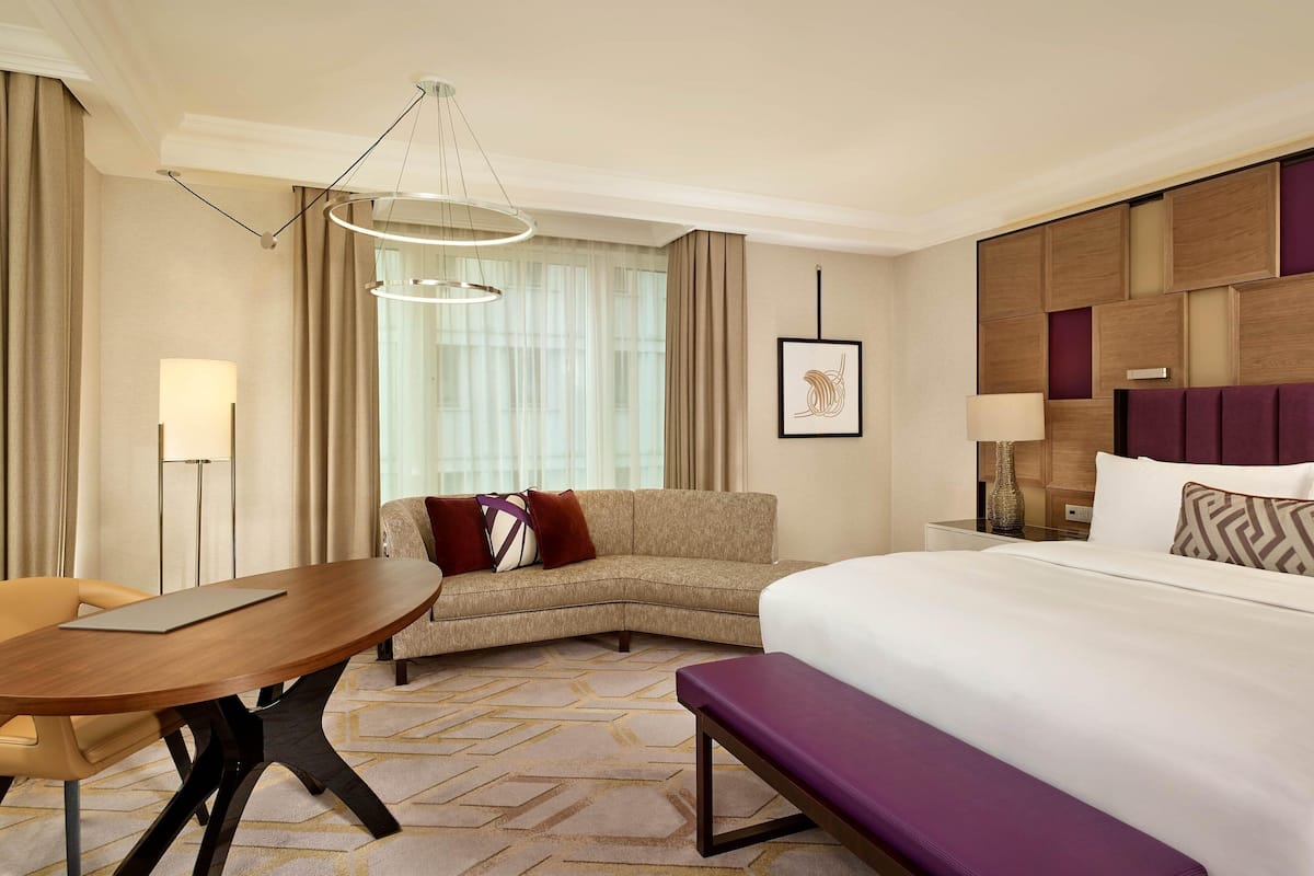 Una habitación de hotel con cama, sofá, mesa de comedor y candelabro.