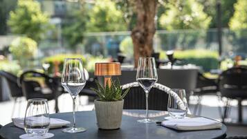 A round table with four wine glasses, a small potted plant, and a table lamp.