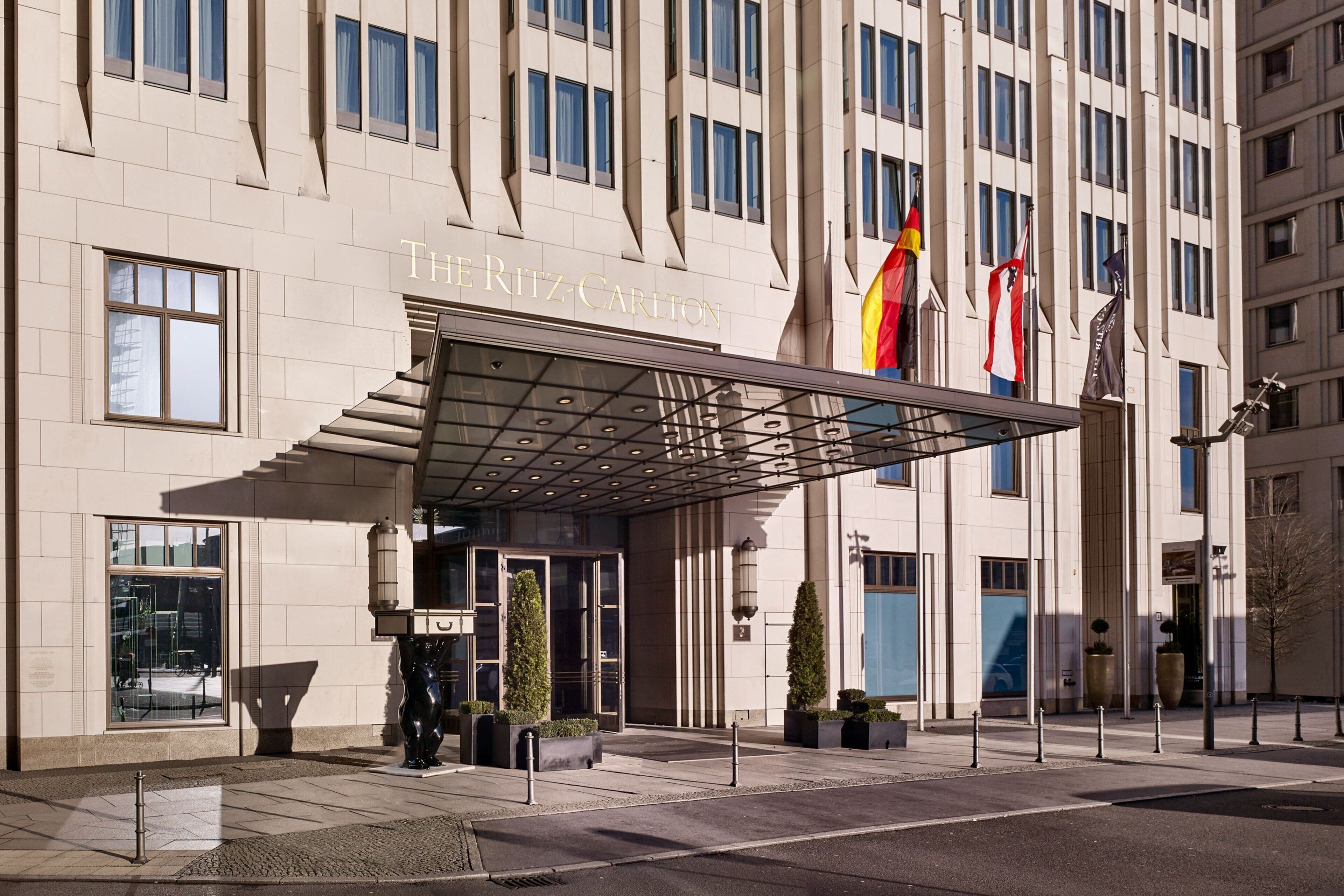 A hotel entrance with a covered entrance, large windows, and flags.
