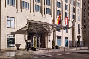 A hotel entrance with a covered entrance, large windows, and flags. - The Ritz-Carlton, Berlin (Berlin)