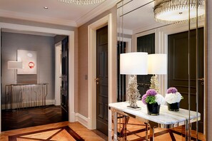 A modern hotel lobby with a marble reception desk, a large mirror, and a chandelier.