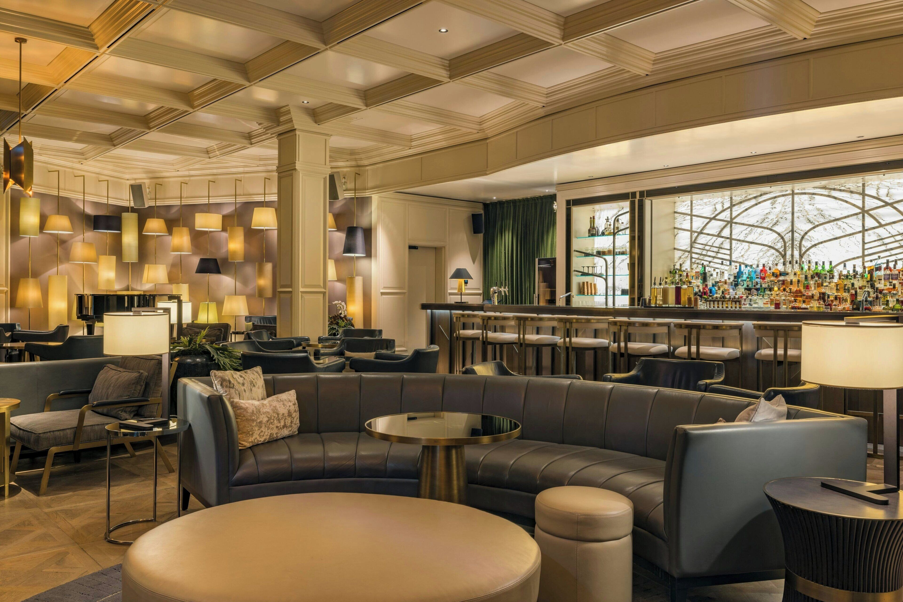 Eine moderne Hotelhalle mit Ledersitzgelegenheiten, einer Bar und Pendelleuchten.