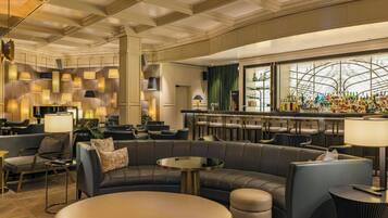 Eine moderne Hotelhalle mit Ledersitzgelegenheiten, einer Bar und Pendelleuchten.