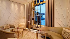 Una sala de estar moderna con un ventanal grande, un sofá, un sillón y una estantería decorativa.