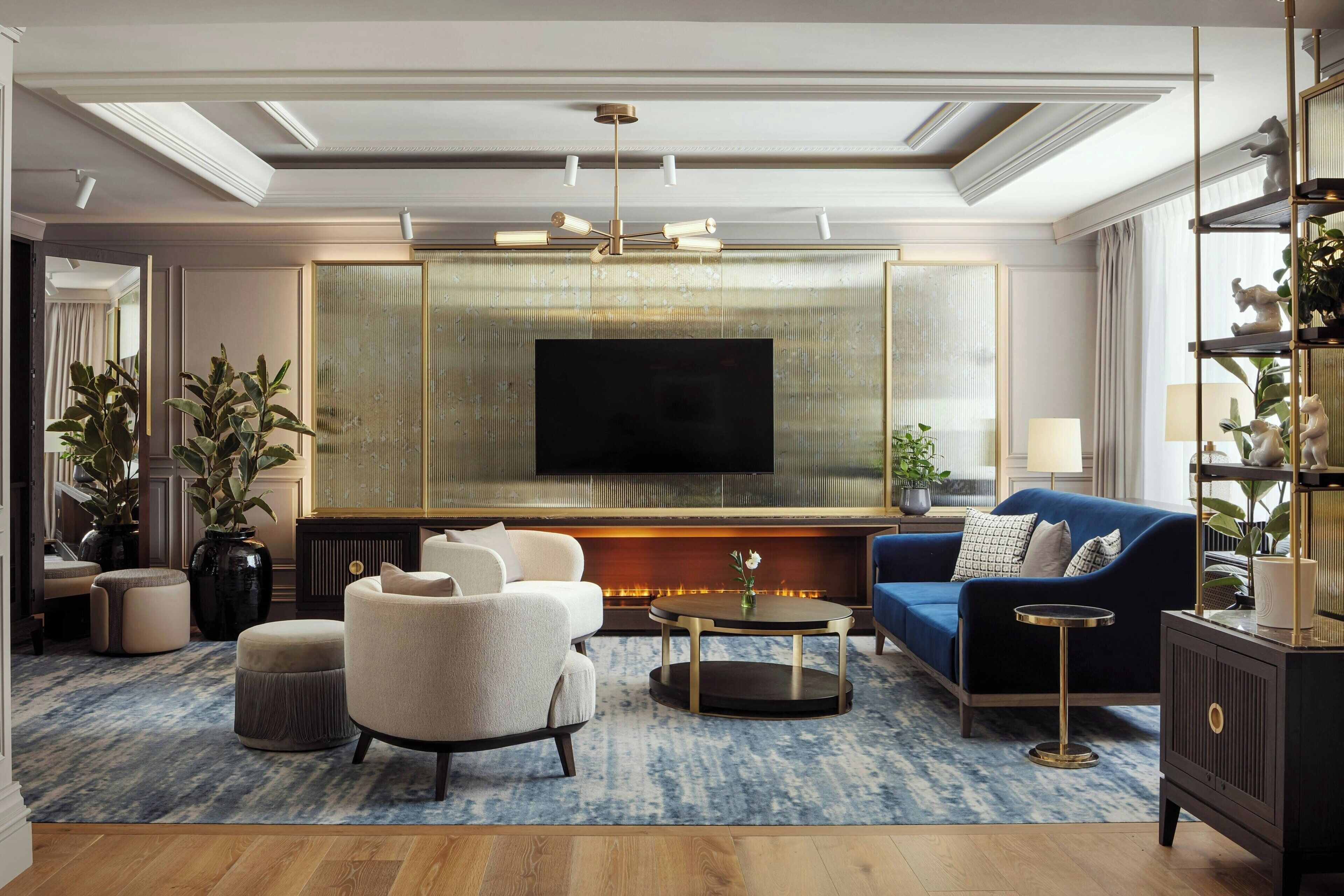 Una sala de estar moderna con un televisor de pantalla plana grande, un sofá azul, un sillón beige y una mesa de centro.