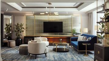 Una sala de estar moderna con un televisor de pantalla plana grande, un sofá azul, un sillón beige y una mesa de centro.