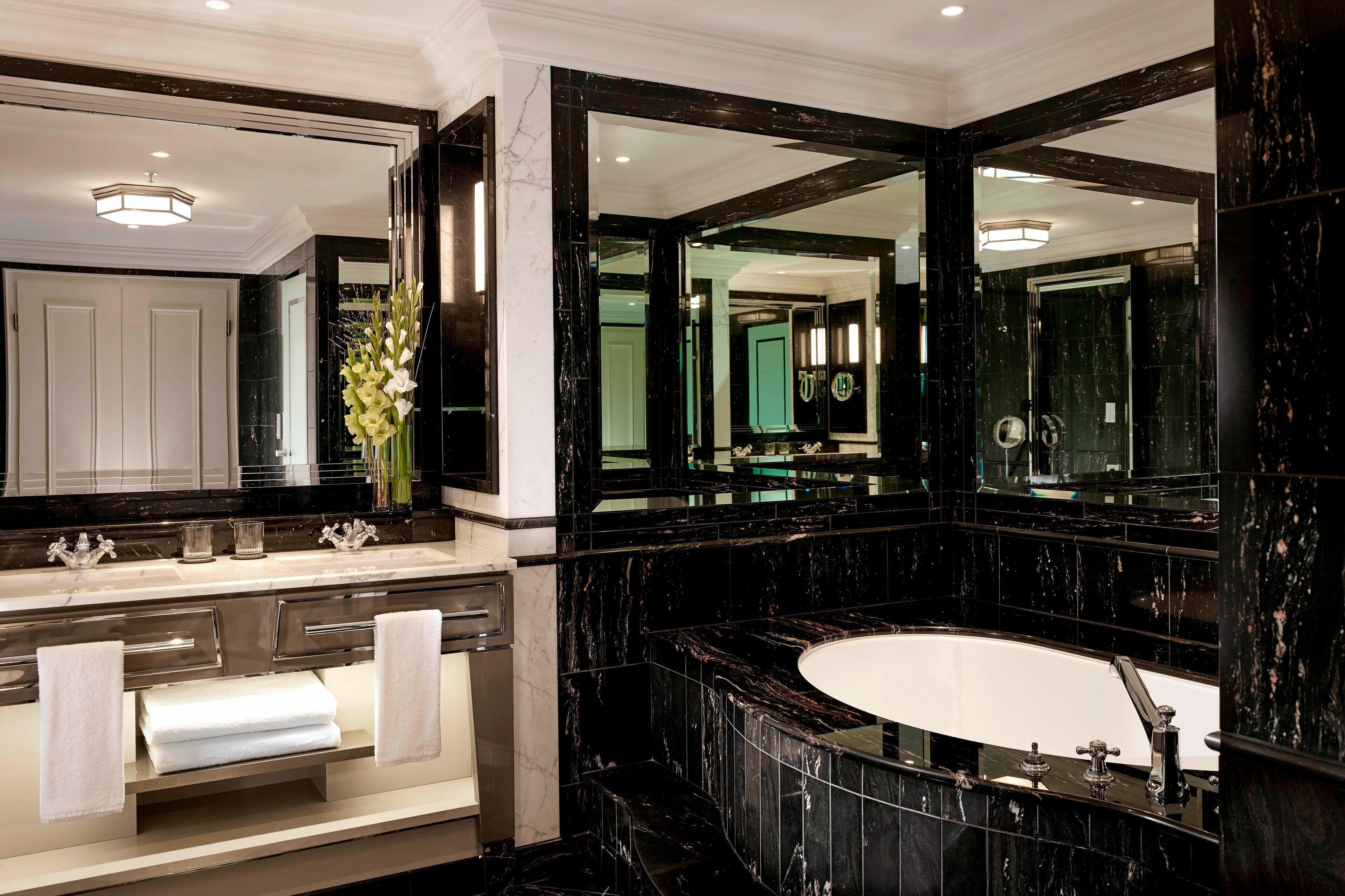 A luxurious bathroom with a large mirror, a bathtub, and a vanity with a sink and towel rack.