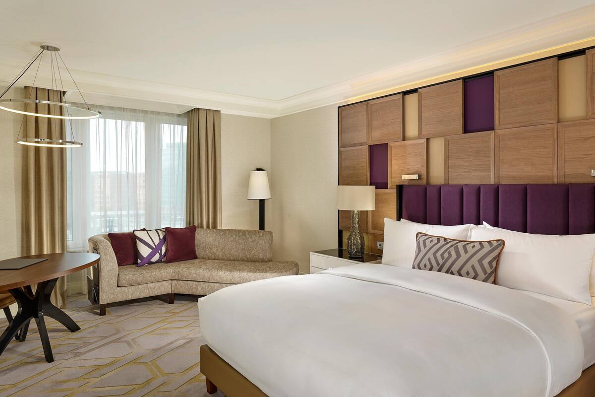 Habitación de hotel con una cama grande, un sofá, un escritorio y una lámpara.