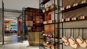 A modern kitchen with copper pots and pans on shelves and hanging racks.