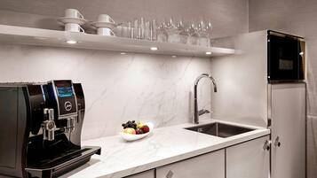 Una cocina moderna con cafetera integrada, frutero, pileta y microondas.