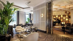 A spacious lobby with a grand piano, comfortable seating, and a large potted plant.