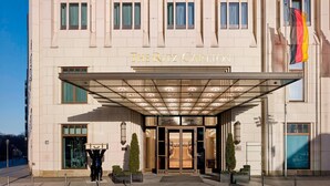 A hotel entrance with a large glass door, a flag, and a sign reading "The Ritz-Carlton".