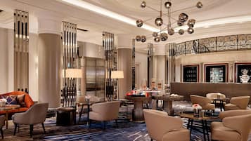 A spacious lobby with a grand chandelier, plush seating, and a bar area.