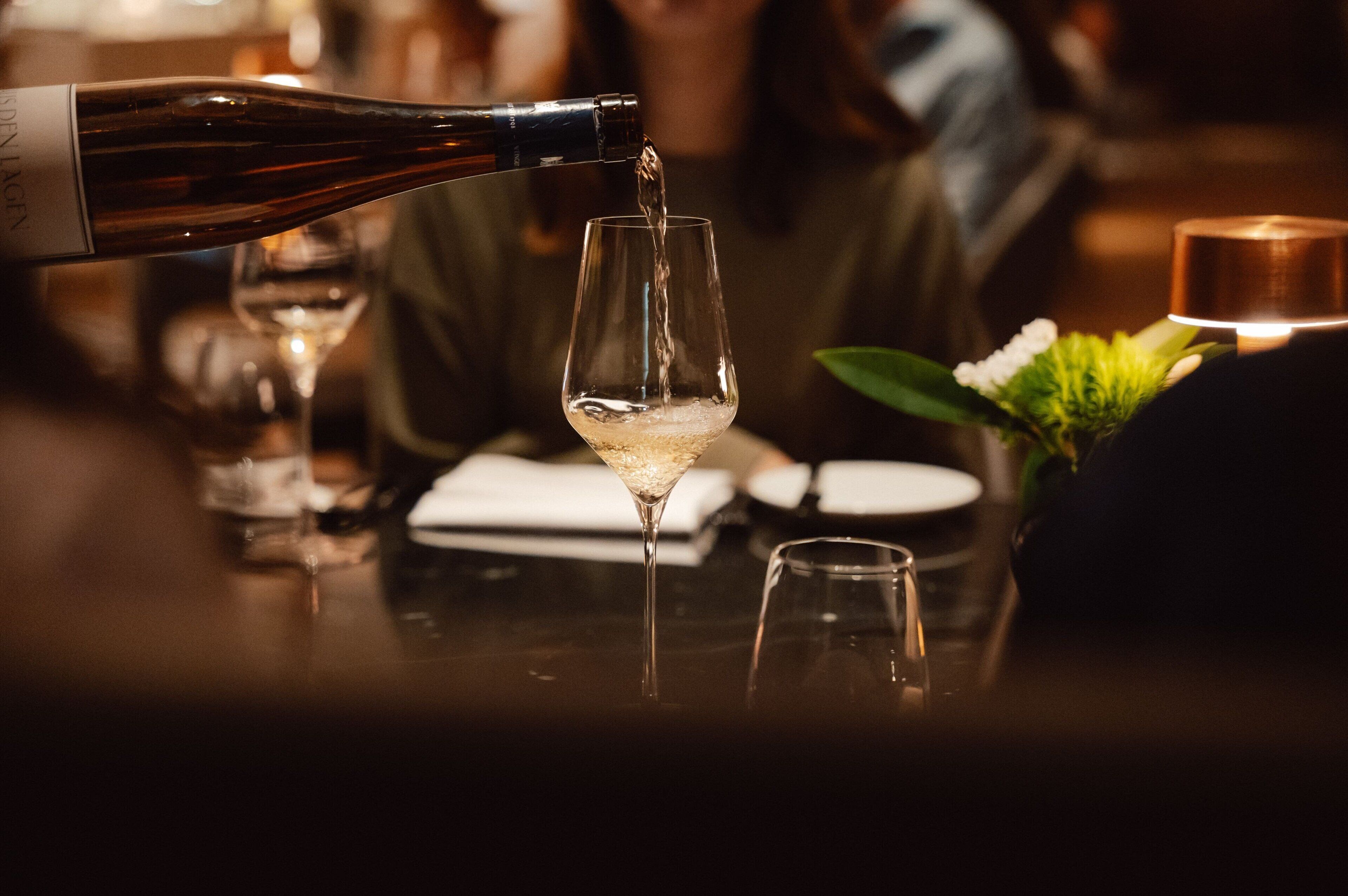 A bottle of wine being poured into a glass.