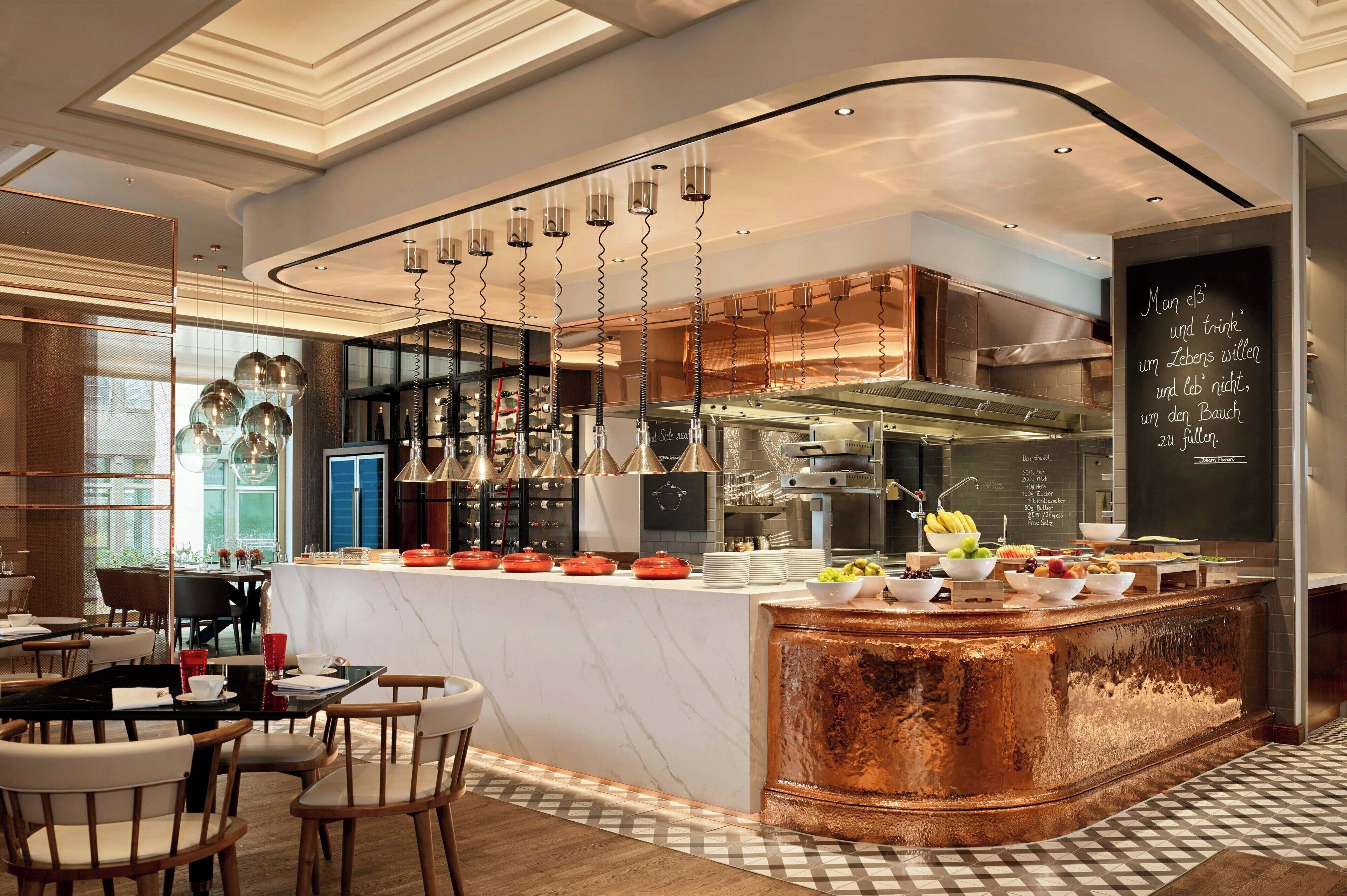 A modern restaurant with a marble counter, hanging lights, and a chalkboard menu.
