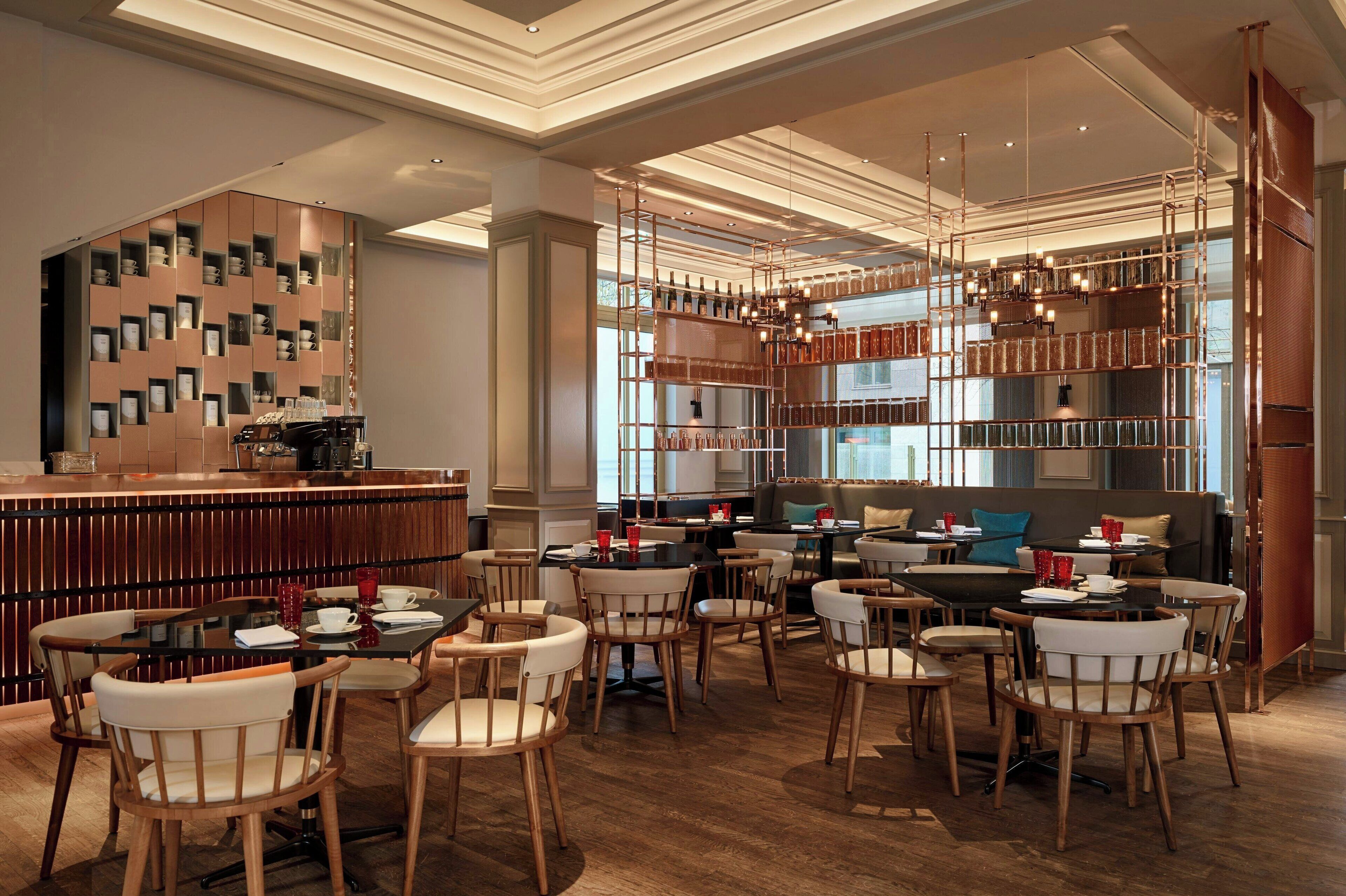 Un restaurante moderno con muebles de madera, una zona de bar y una pared decorativa con estanterías.