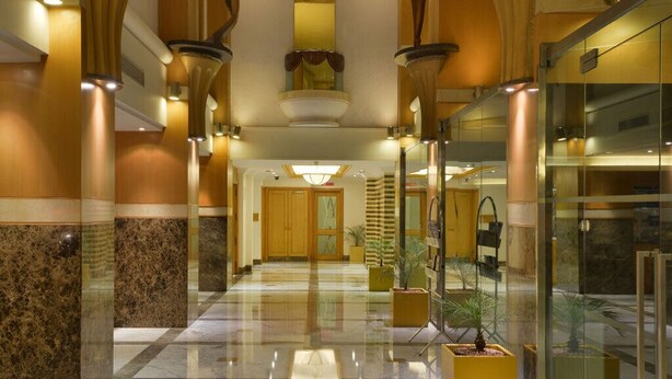 A spacious lobby with marble flooring, large columns, and modern lighting fixtures.