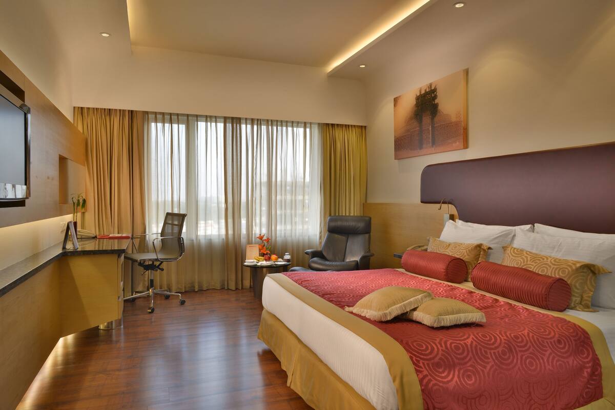 Une chambre d’hôtel avec un grand lit, un bureau, une chaise et un téléviseur.