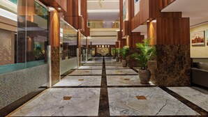 A spacious lobby with a marble floor, wooden paneling, and a large chandelier.