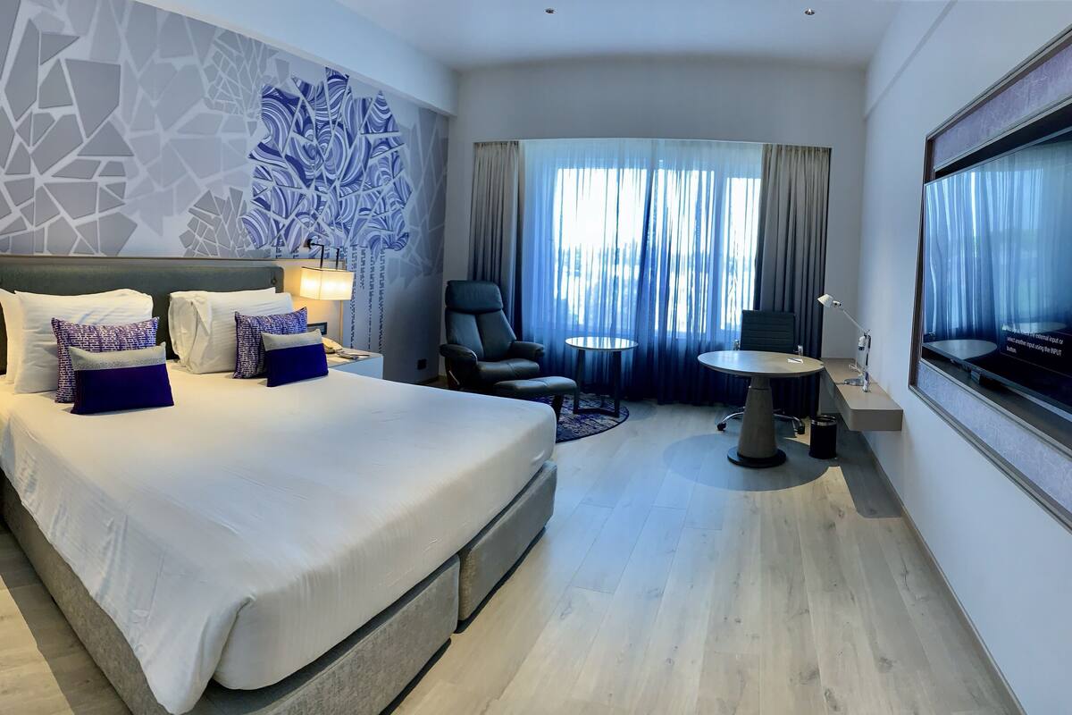 Une chambre d’hôtel moderne équipée d’un grand lit, d’un bureau, d’une chaise et d’une télévision.