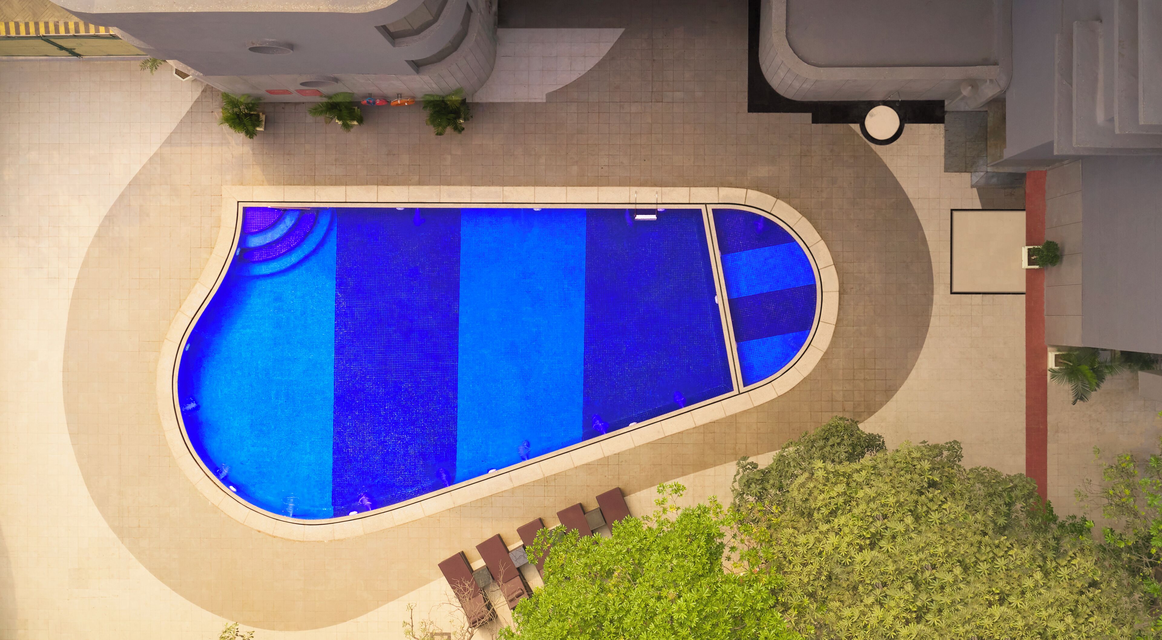 An outdoor swimming pool with a tiled deck and a curved edge.