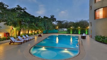 Una piscina al aire libre, sillones reclinables de piscina