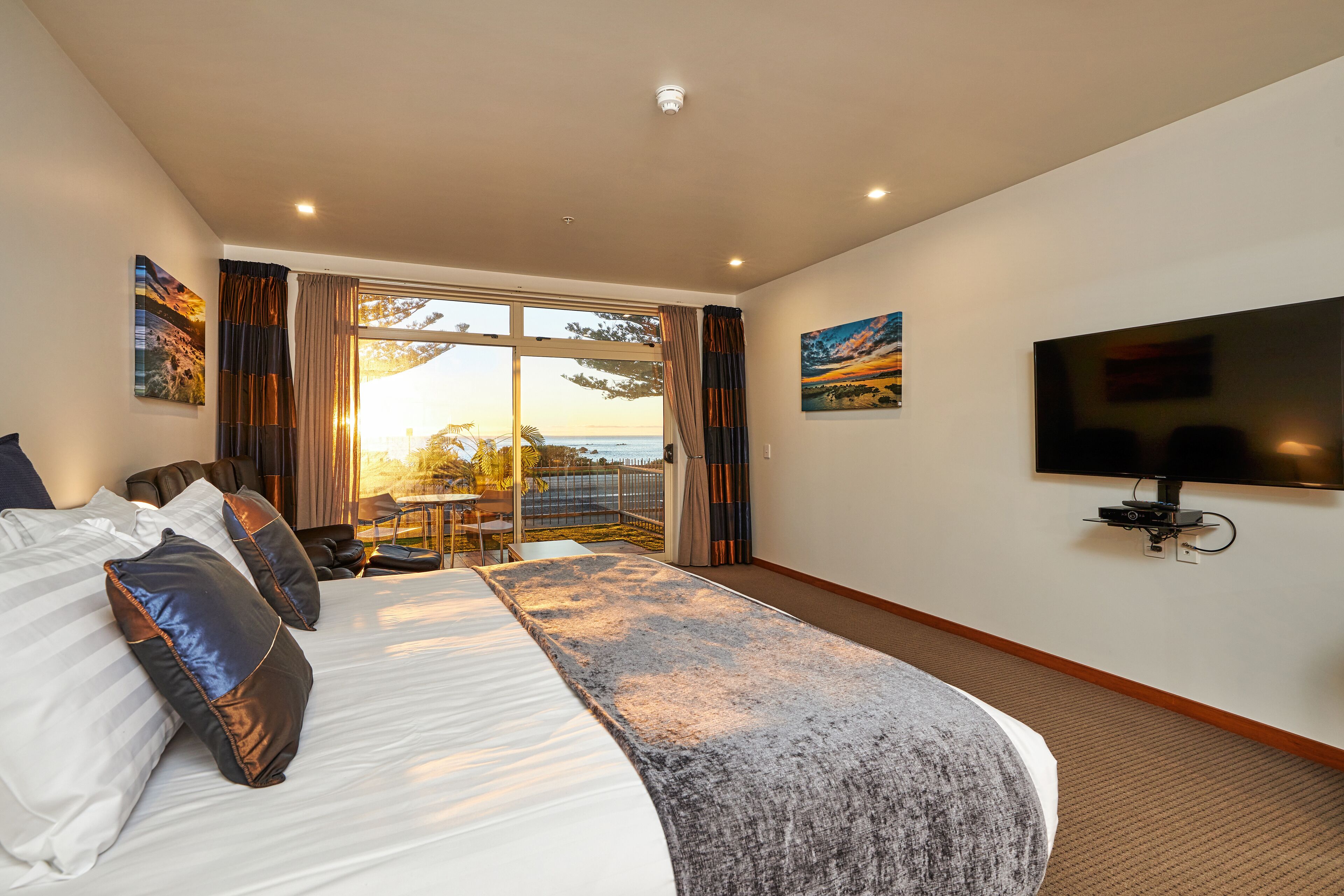 A hotel room with a large bed, a TV, and a balcony with a view.