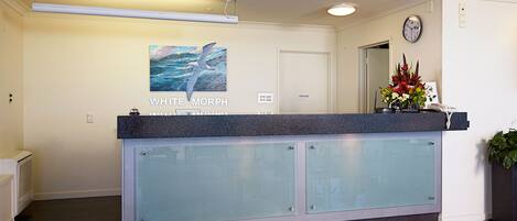 A reception desk with a glass panel, a clock, and a framed artwork on the wall.