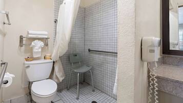 A bathroom with a toilet, a shower with a grab bar, a hairdryer, and a towel rack.