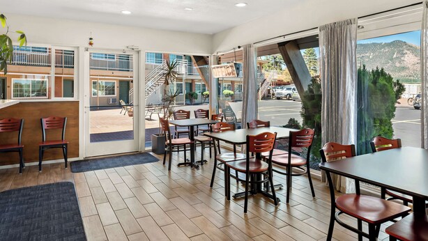 A restaurant with a view of a mountain, wooden flooring, and a mix of red and black chairs. - Americas Best Value Inn & Suites Flagstaff (Flagstaff)