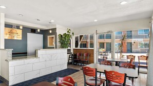 A hotel reception area with a marble counter, a sign for 'Americas Best Value Inn & Suites', and a view of the outdoor seating area with tables and chairs. - Americas Best Value Inn & Suites Flagstaff (Flagstaff)
