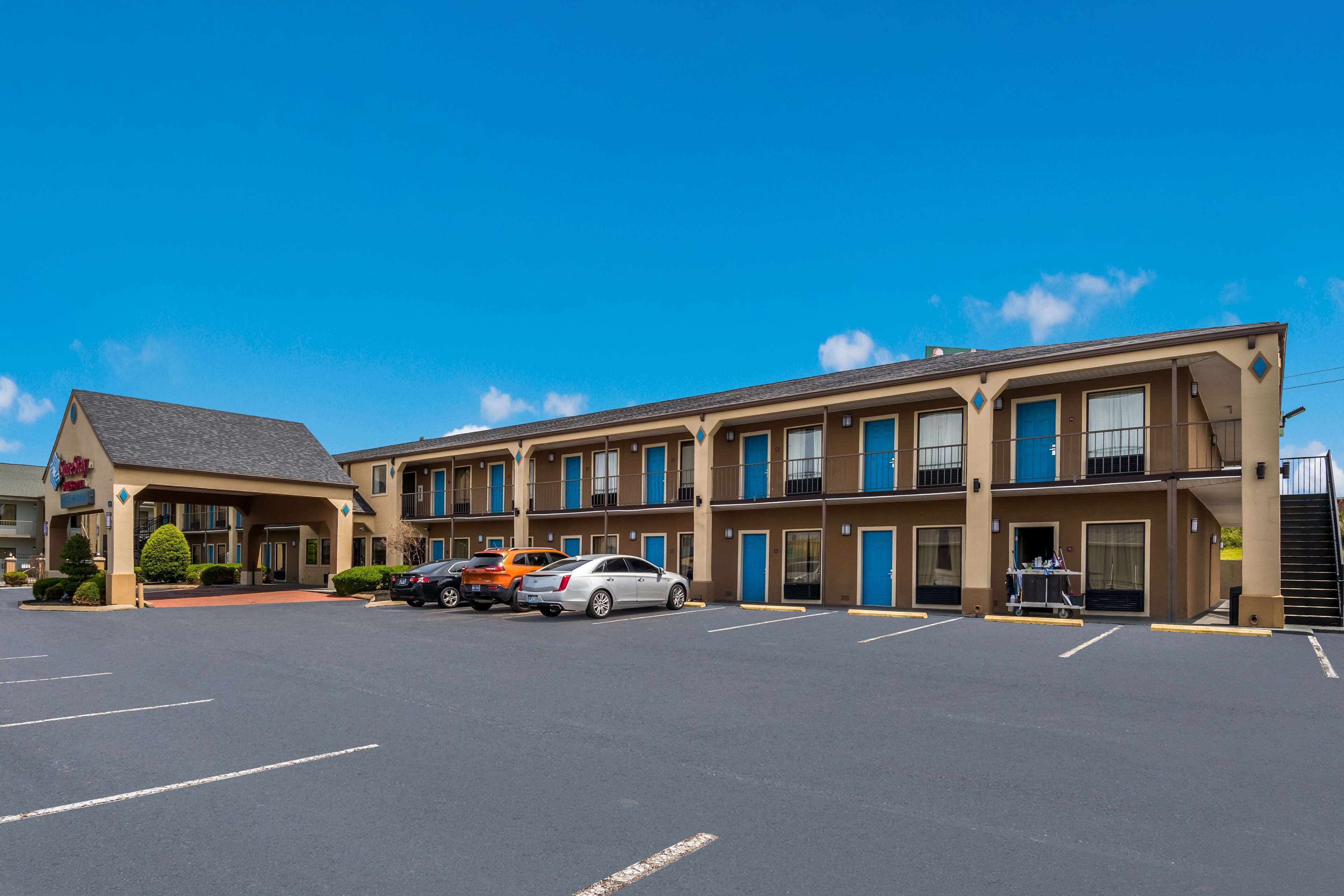 A motel with a parking lot, multiple units, and a small outdoor seating area.