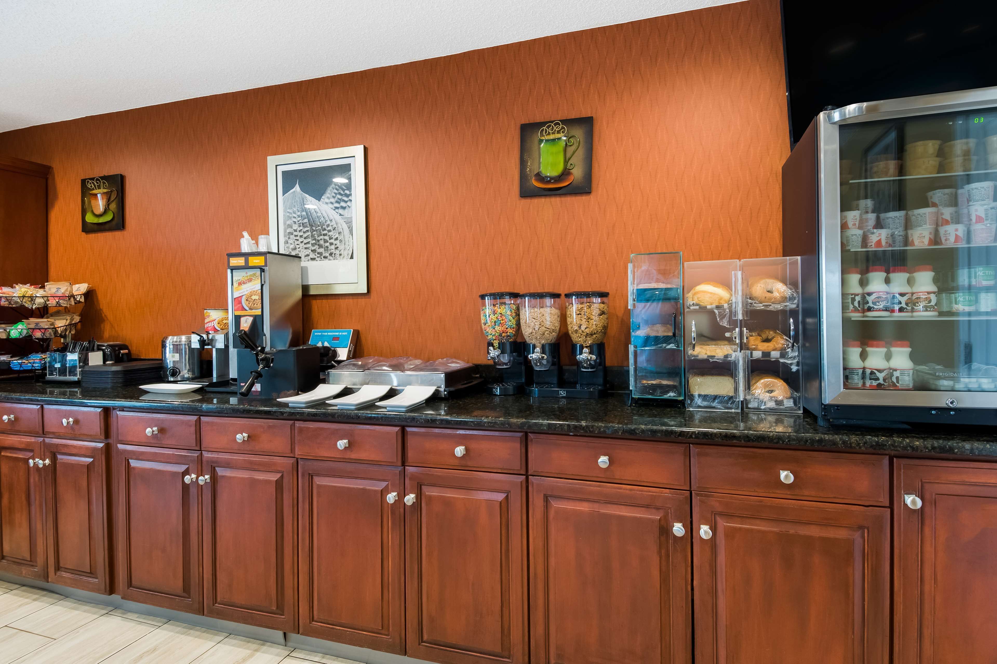 Una barra de desayuno con máquinas de café, un refrigerador con cartones de leche y un dispensador de café.