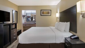 A hotel room with a large bed, a desk with a telephone, a television, a mirror, and a bathroom visible through an open door. - SureStay Plus Hotel by Best Western Jackson (Jackson)