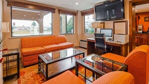A modern living room with a sofa, a glass coffee table, a desk with a computer, and a TV. - SureStay Plus Hotel by Best Western Jackson (Jackson)