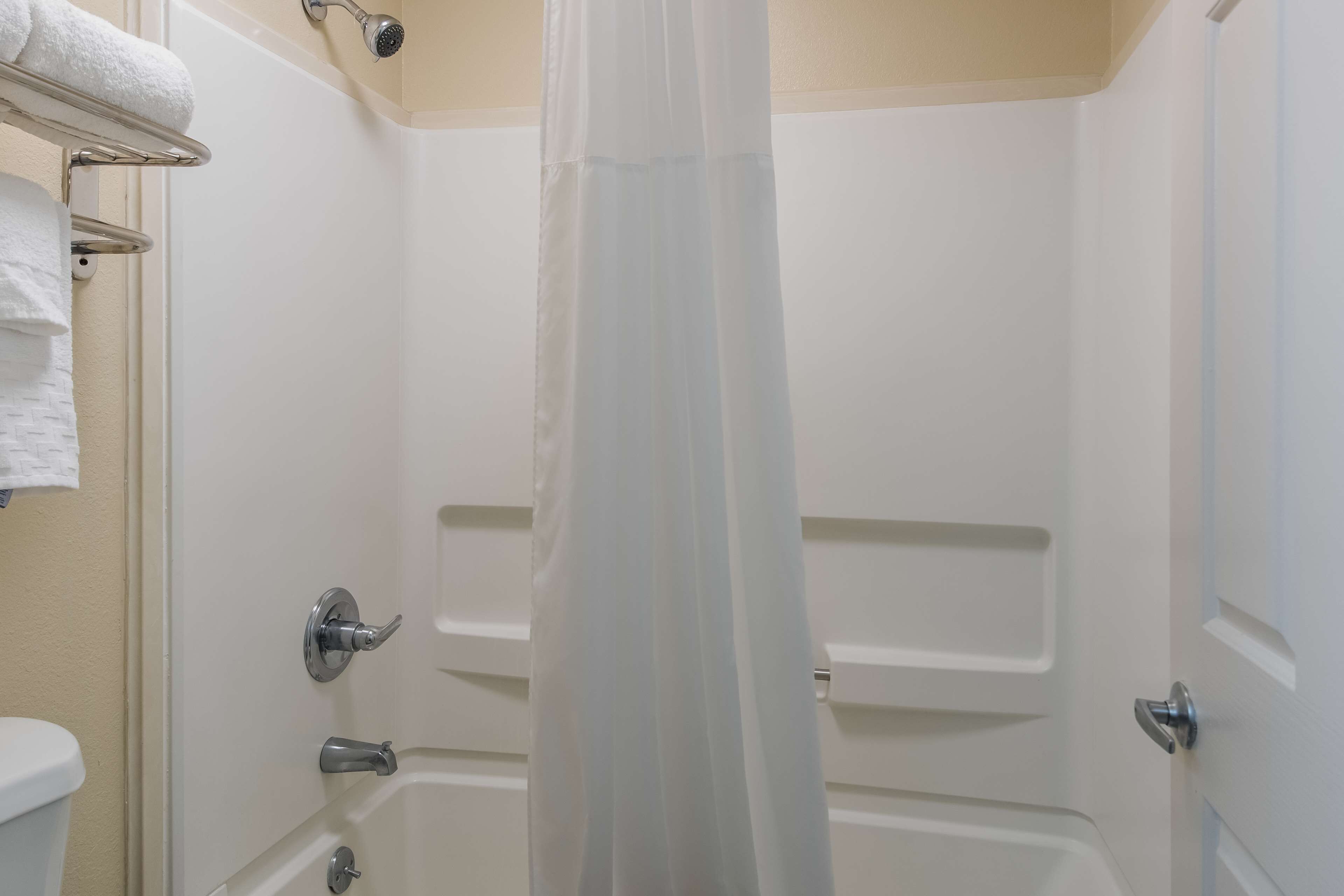 Un baño con una bañera, una cortina de ducha y un perchero con toallas.