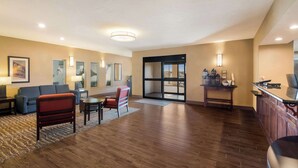 A spacious living area with a wooden floor, a sofa, a chair, a coffee table, and a kitchen area with a counter and cabinets.