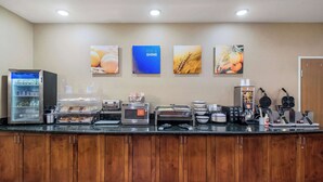Una barra de desayuno con varios dispensadores de alimentos y bebidas, que incluyen una máquina de café, un tostador y un mostrador refrigerado.
