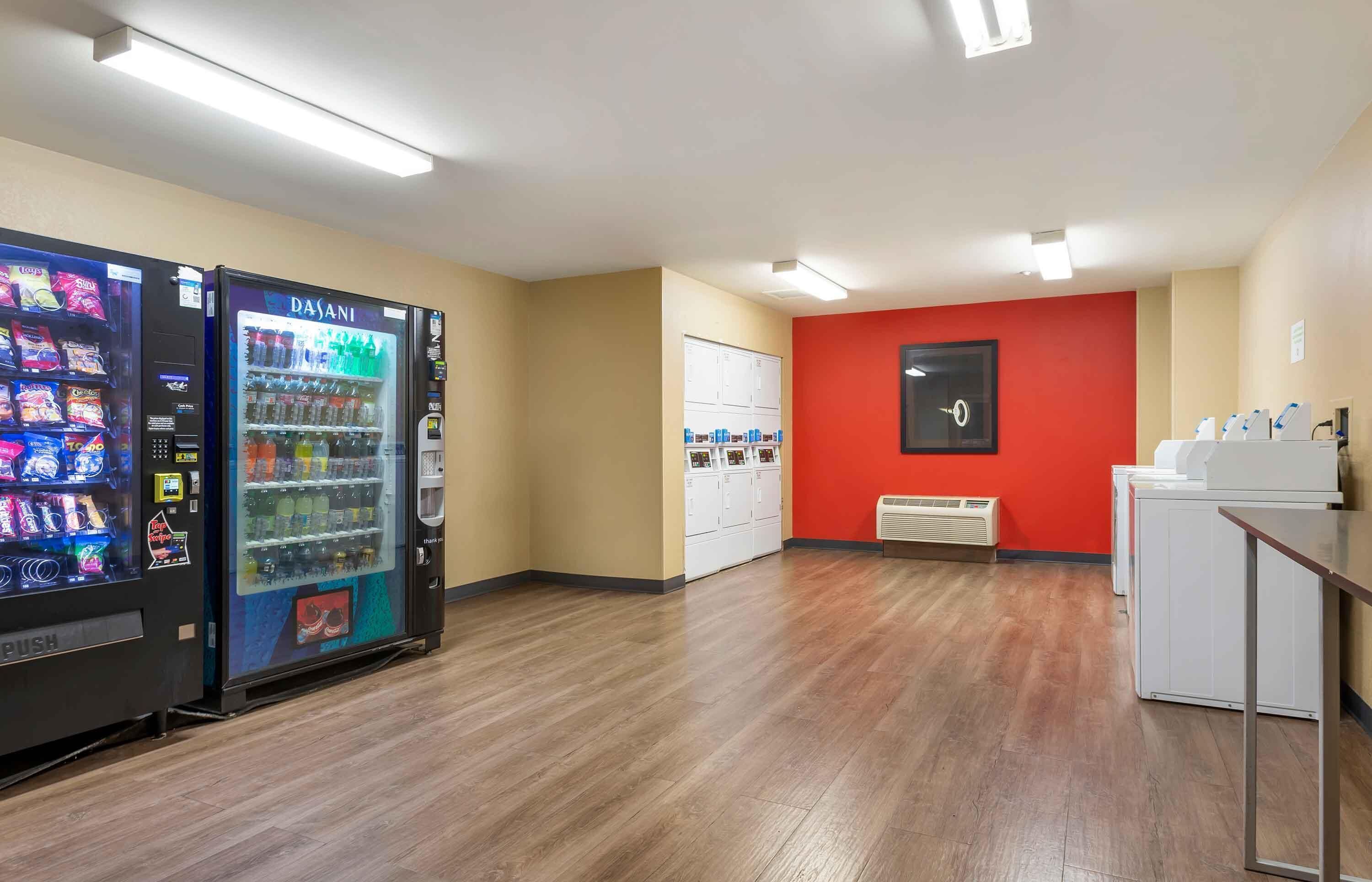 A room with a vending machine, a red wall, and a white cabinet.