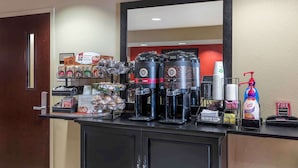 A coffee station with multiple coffee makers, disposable cups, and a fire extinguisher.