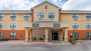 A hotel lobby with a stone facade, multiple windows, and a clear sky.