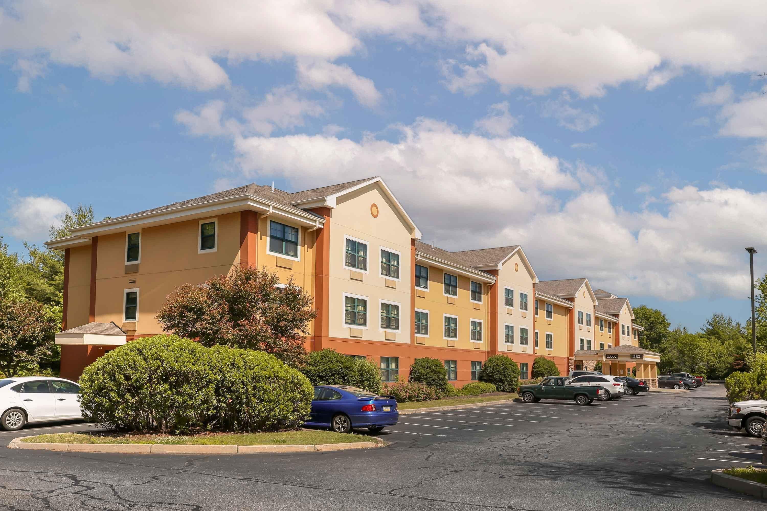 A hotel with a modern design, featuring multiple floors and a parking lot.