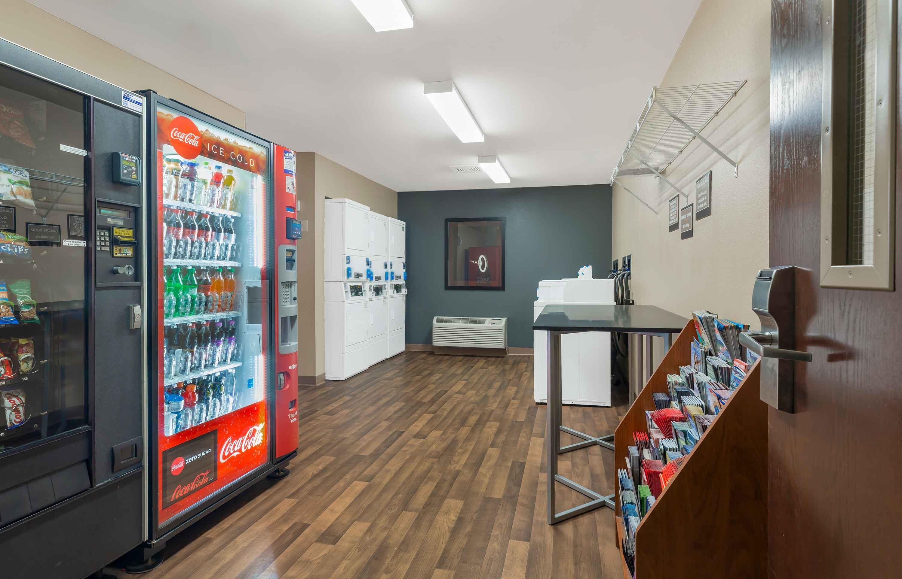 A hotel lobby with vending machines, a reception desk, and a bulletin board.