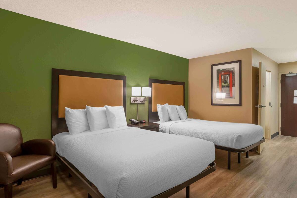 Habitación de hotel con dos camas, un escritorio, una silla y una puerta.