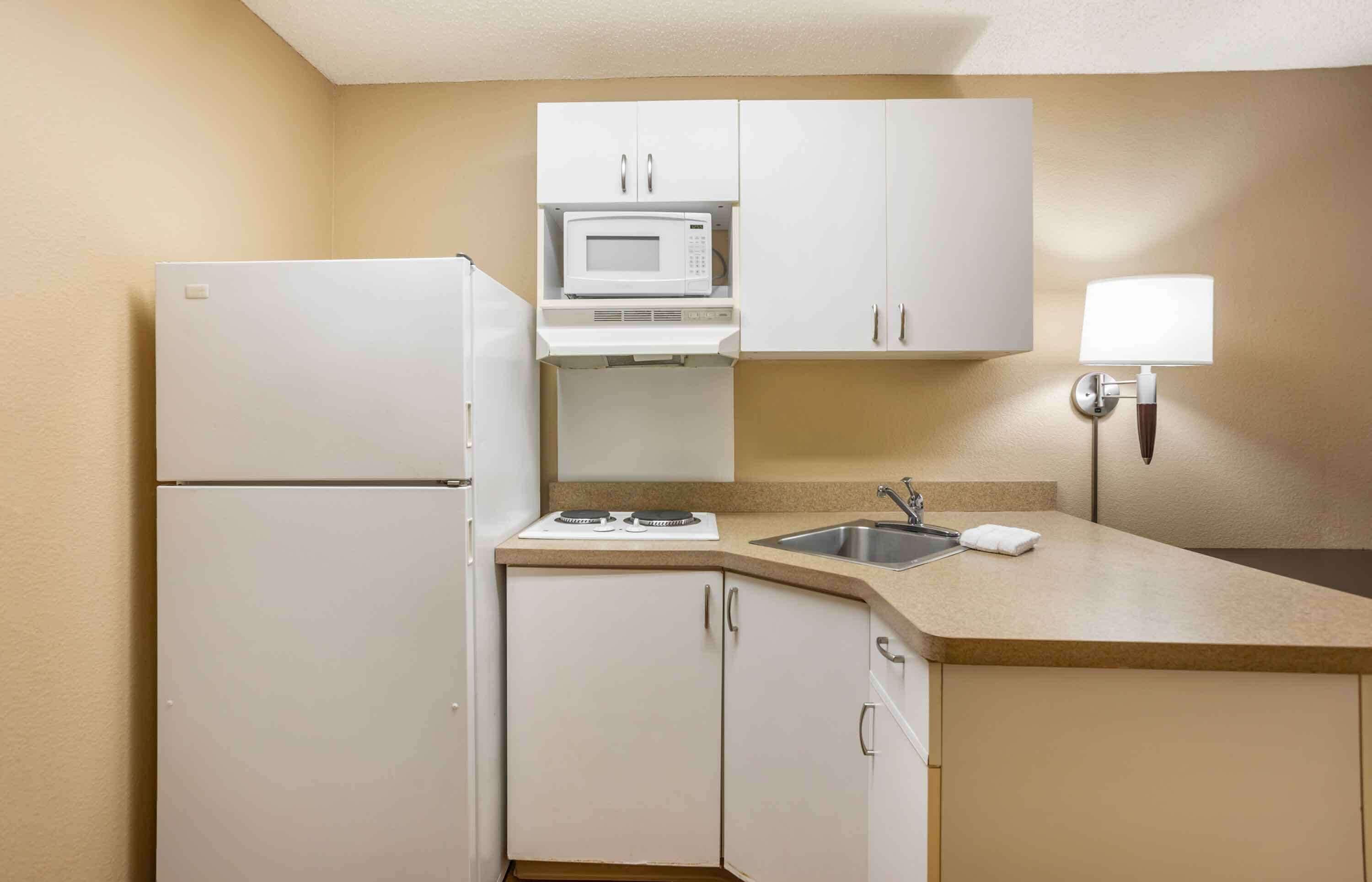 A compact kitchen with a refrigerator, microwave, stove, sink, and cabinets.