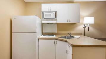 A compact kitchen with a refrigerator, microwave, stove, sink, and cabinets.