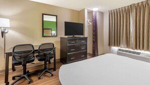A hotel room with a bed, a desk with two office chairs, a television, a dresser, a mirror, and a window with curtains. - Extended Stay America Select Suites - Columbia - Stadium Blvd. (Columbia)