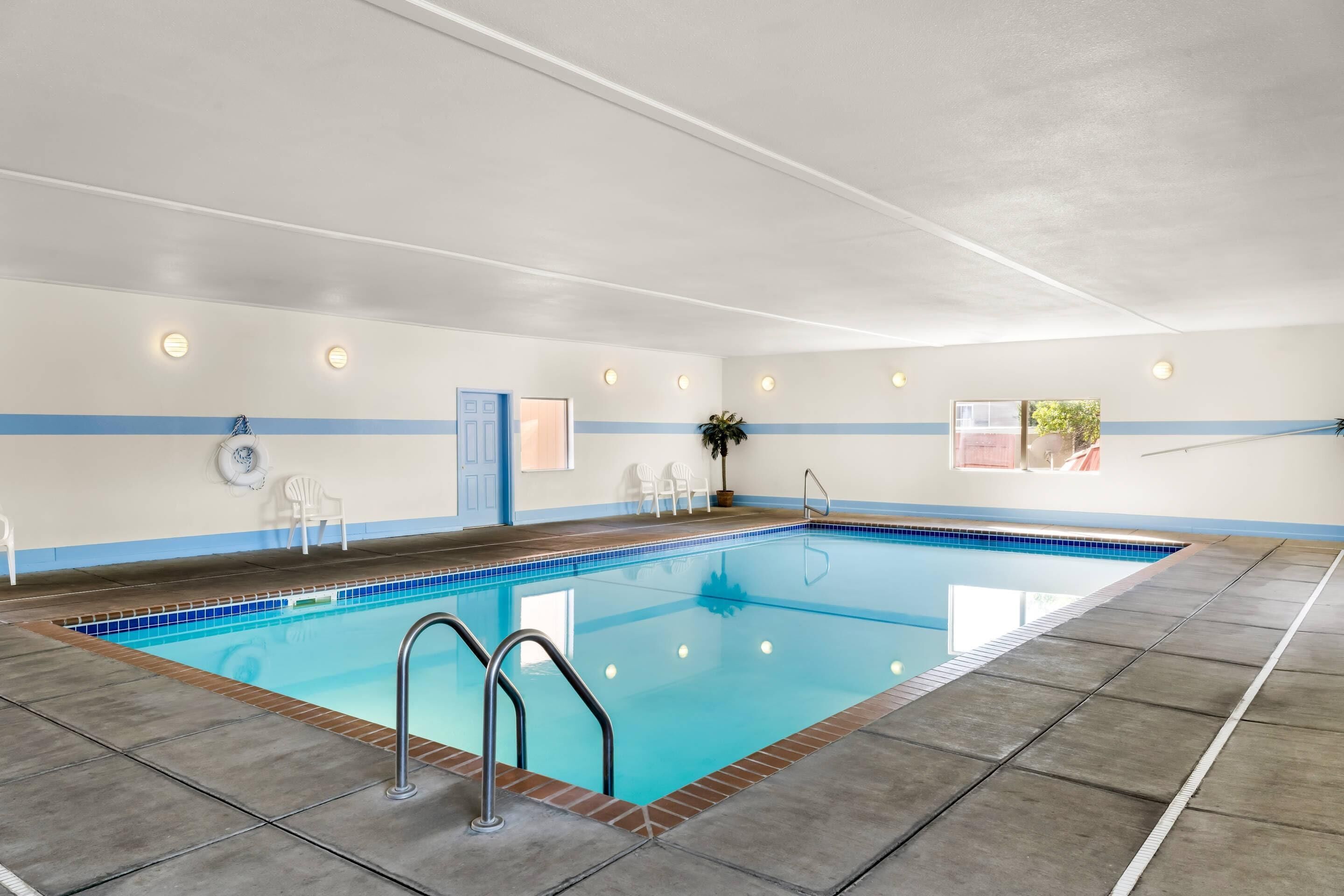 A swimming pool with a tiled edge, a blue and white wall, and a door.