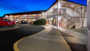 Et hotel med flere etager, en parkeringsplads, en rød lastbil og en trappe til de øvre niveauer.