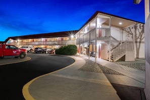 A multi-story hotel with a parking area, a red truck, and a staircase leading to the upper level.